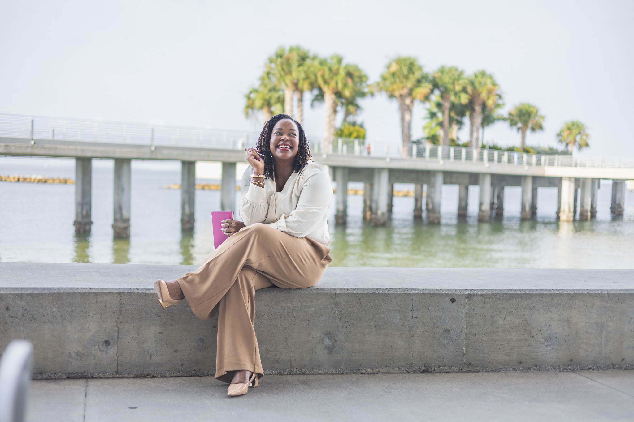 Tiffany Blessing, M.Ed., founder of Seen & Accepted, smiling while seated by the water at St. Pete Pier